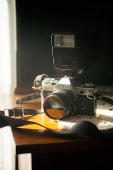 Close-up of a vintage camera on a wooden table with soft natural light highlighting its details.