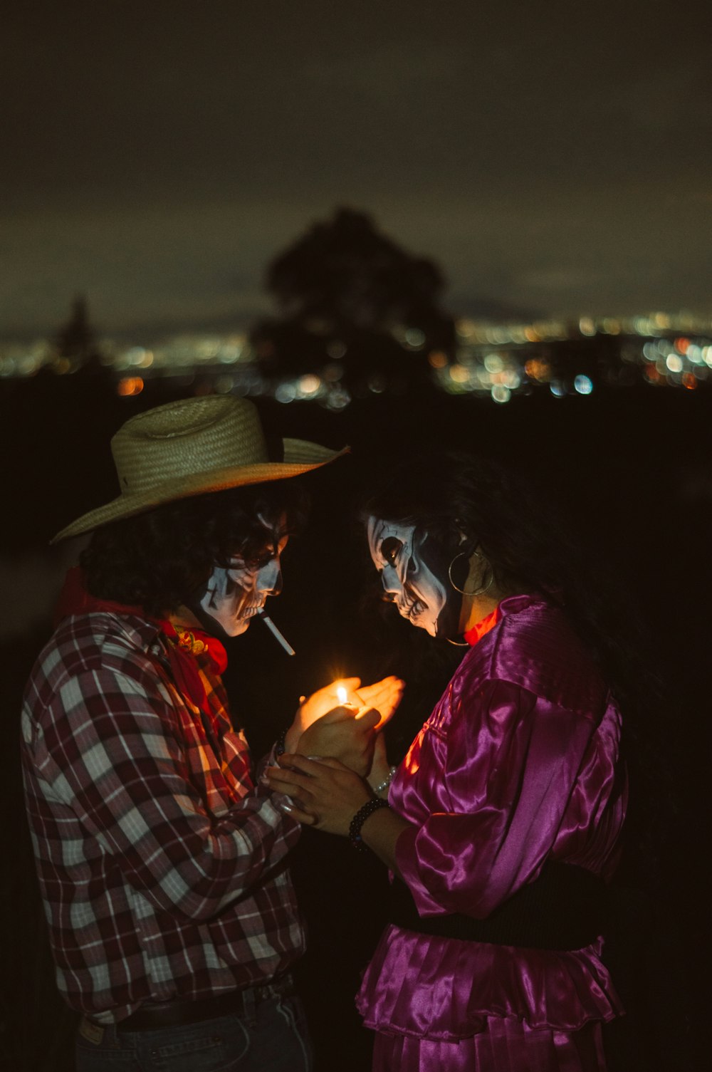 a man and a woman in costumes holding a lit candle