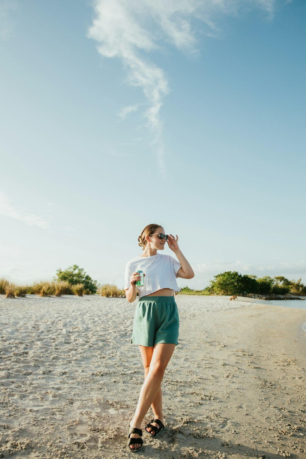 uma mulher em pé no topo de uma praia de areia