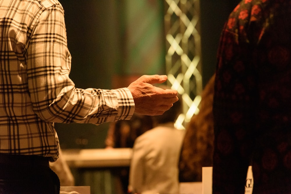 a man standing in front of a crowd holding his hand out