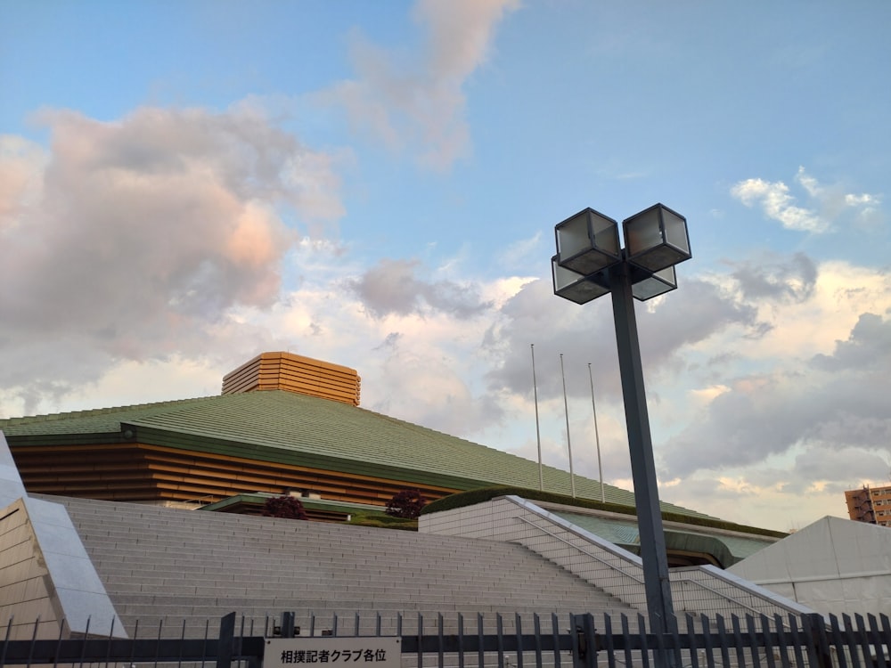 a building with a green roof and a tall light pole