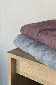 a stack of towels sitting on top of a wooden shelf