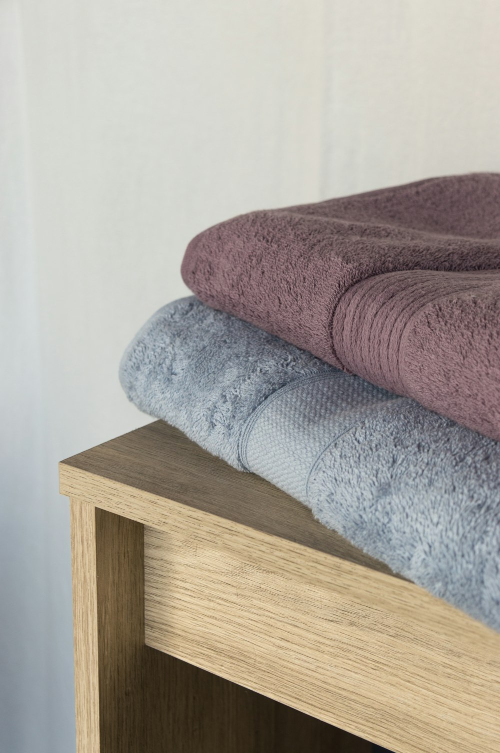 a stack of towels sitting on top of a wooden shelf