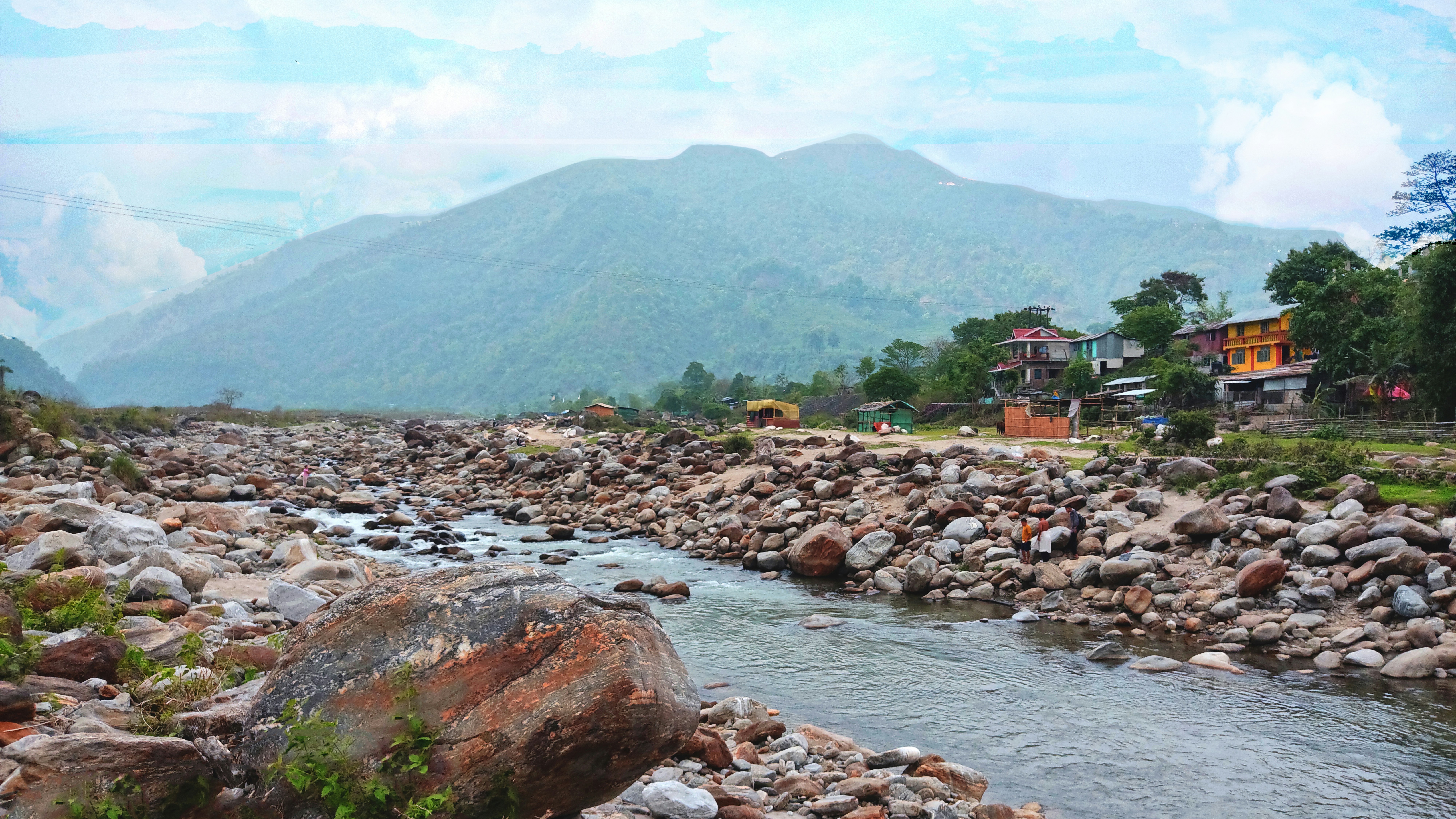 sungai yang mengalir melalui lereng bukit hijau subur