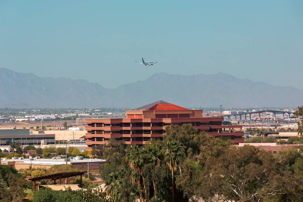 an airplane flying over a city with mountains in the background