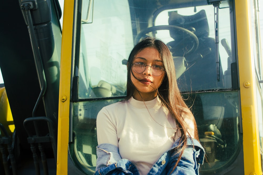 a woman wearing glasses standing in front of a tractor