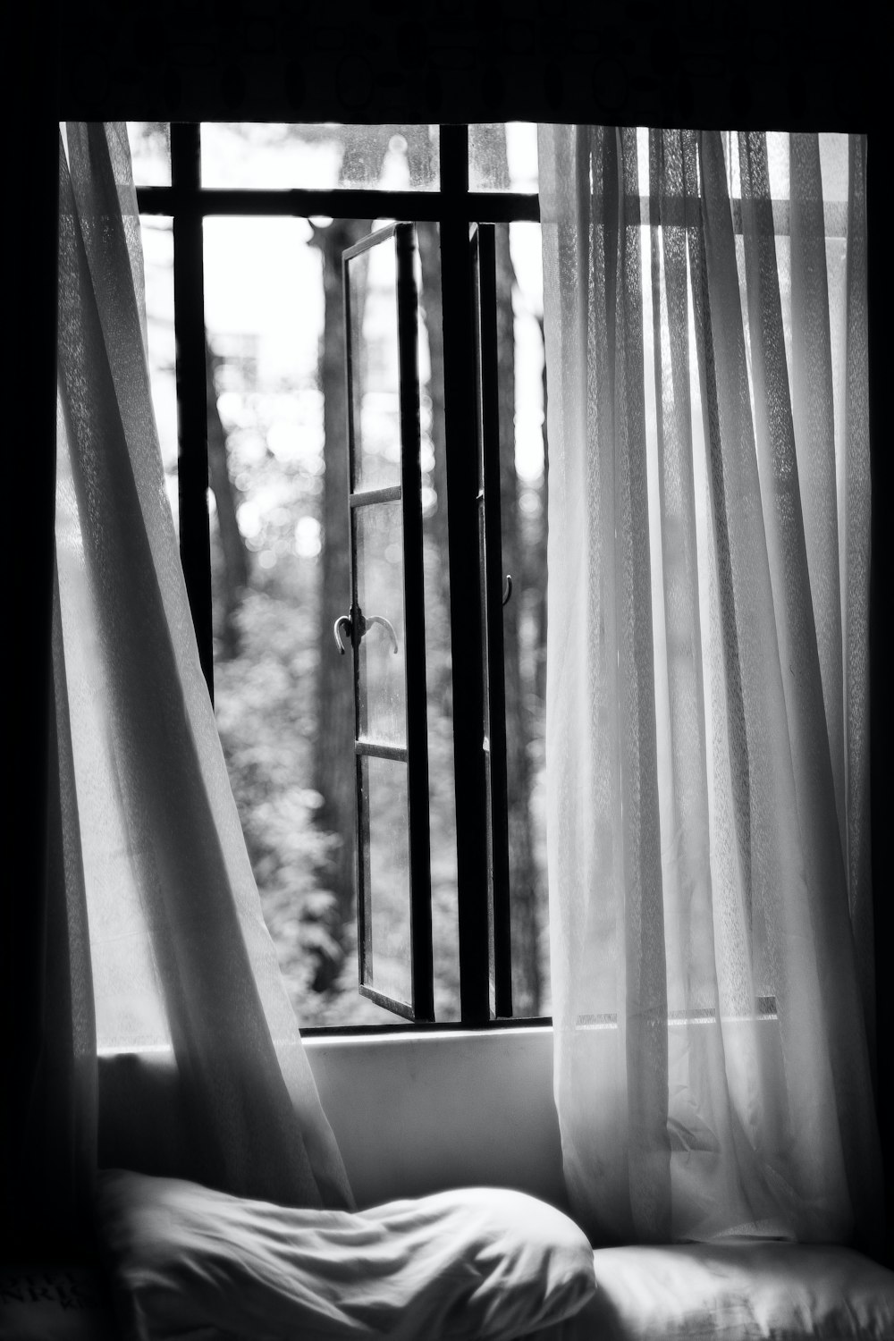 a black and white photo of a window with curtains