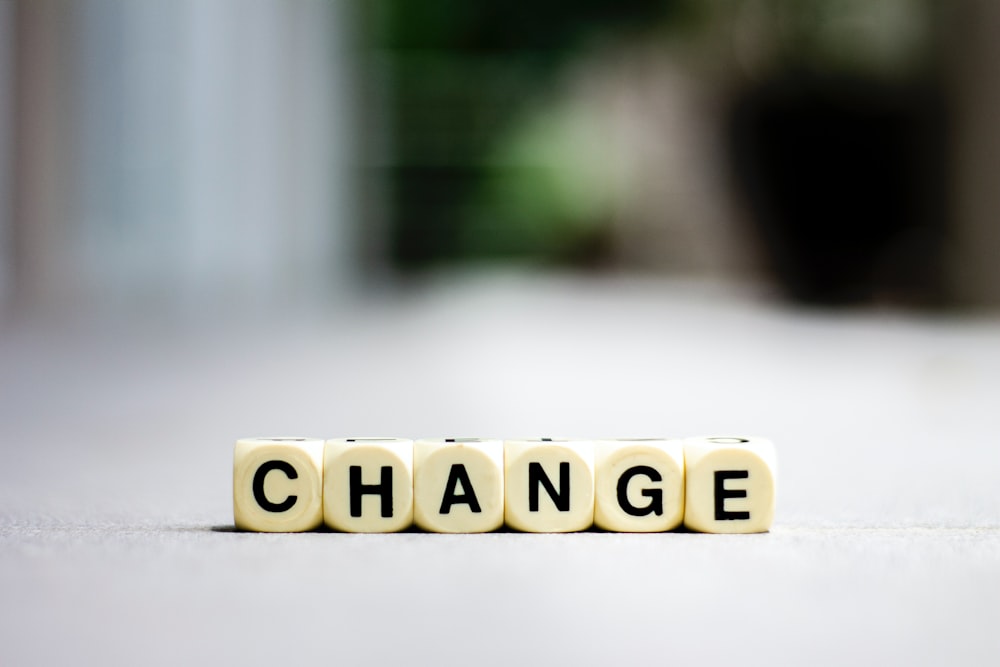 a close up of a scrabble type word that says change