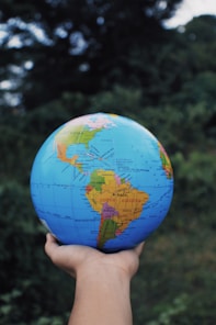 a hand holding a small blue and yellow globe