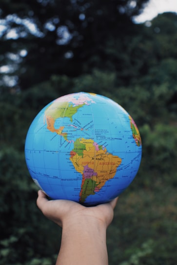a hand holding a small blue and yellow globe