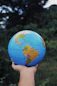 a hand holding a small blue and yellow globe