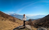 a woman standing on a rock in the mountains