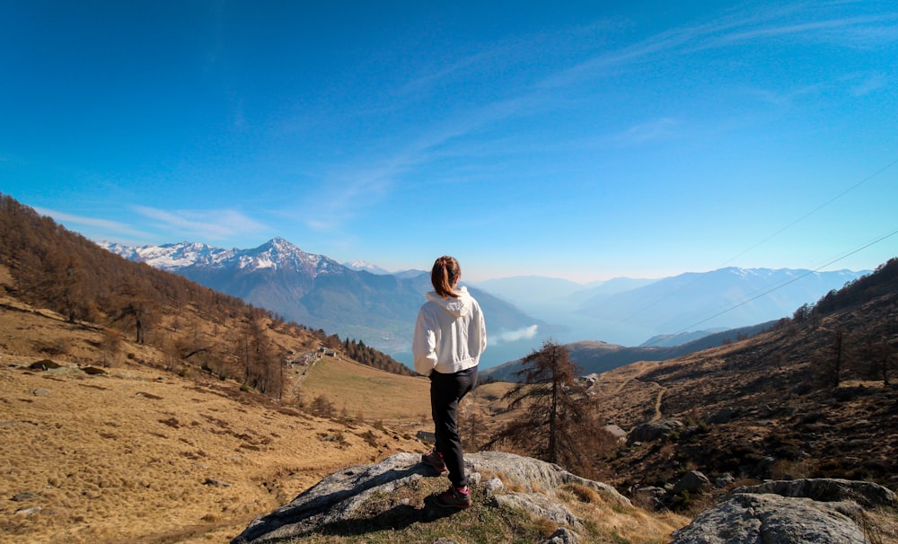 a woman standing on a rock in the mountains