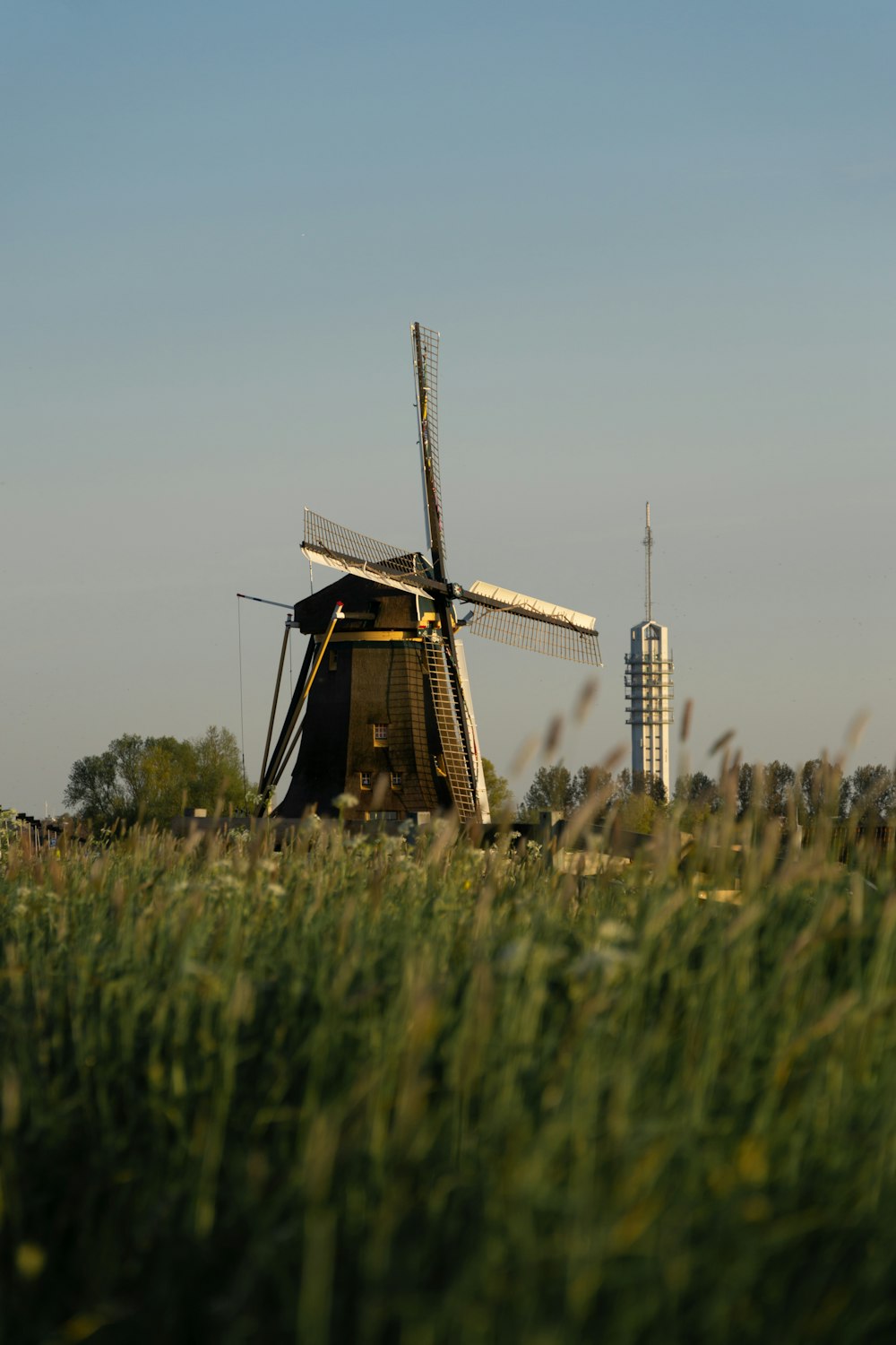 a windmill in a field with tall grass