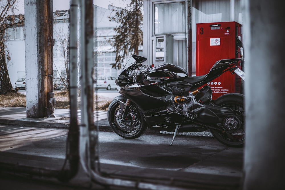 a black motorcycle parked in front of a gas station