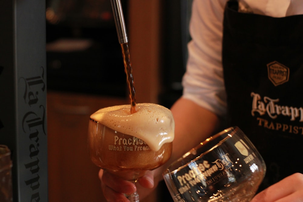 a person pouring a drink into a wine glass