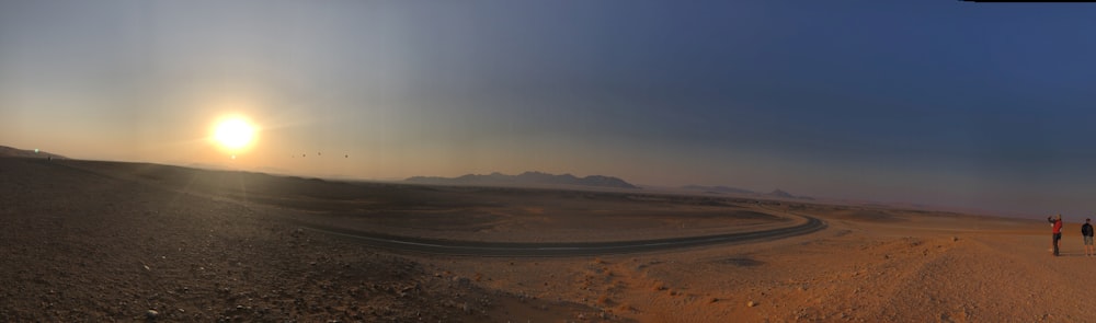 a couple of people walking across a desert