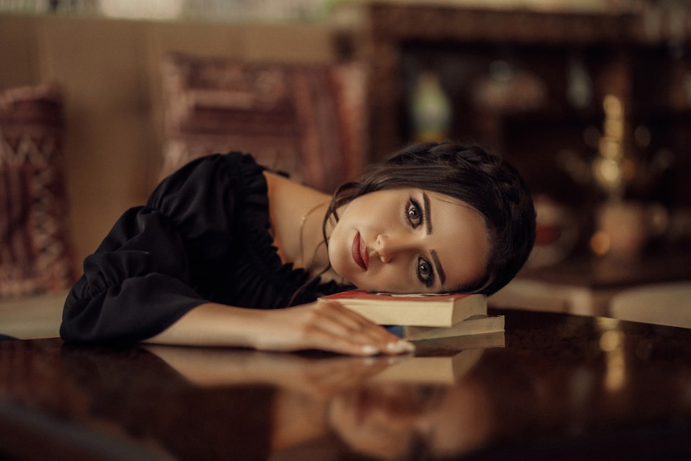 a woman laying on top of a table next to a book