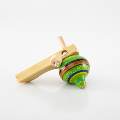 A colorful wooden spinning top with vibrant hues of green, yellow, black, and red is placed beside a wooden handle that has a string attached. The surface is clean and minimalistic, enhancing the prominence of the toy.