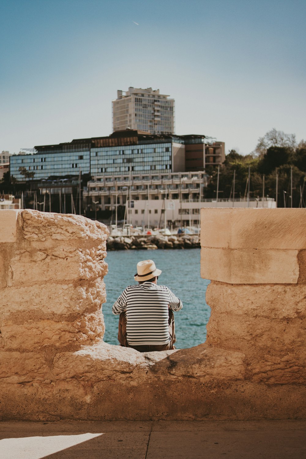 a man sitting on a rock looking out at the water