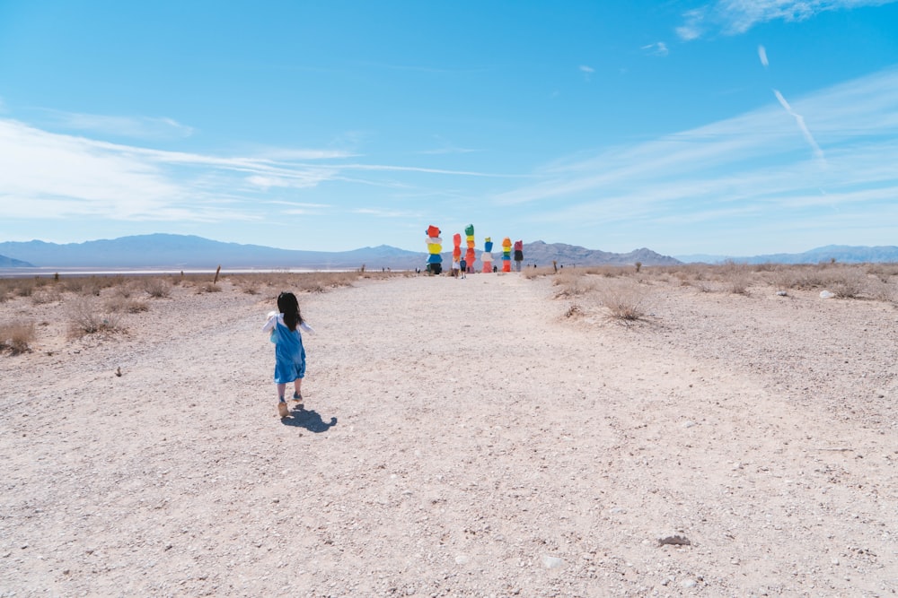 a little girl standing in the middle of a desert