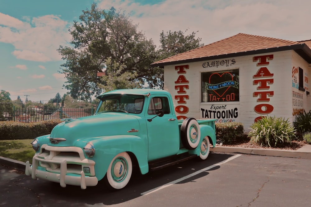 a blue truck parked in front of a tattoo parlor