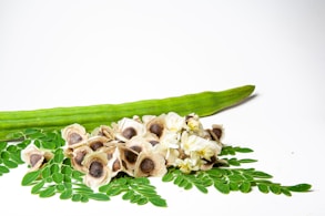a cucumber and some flowers on a white surface