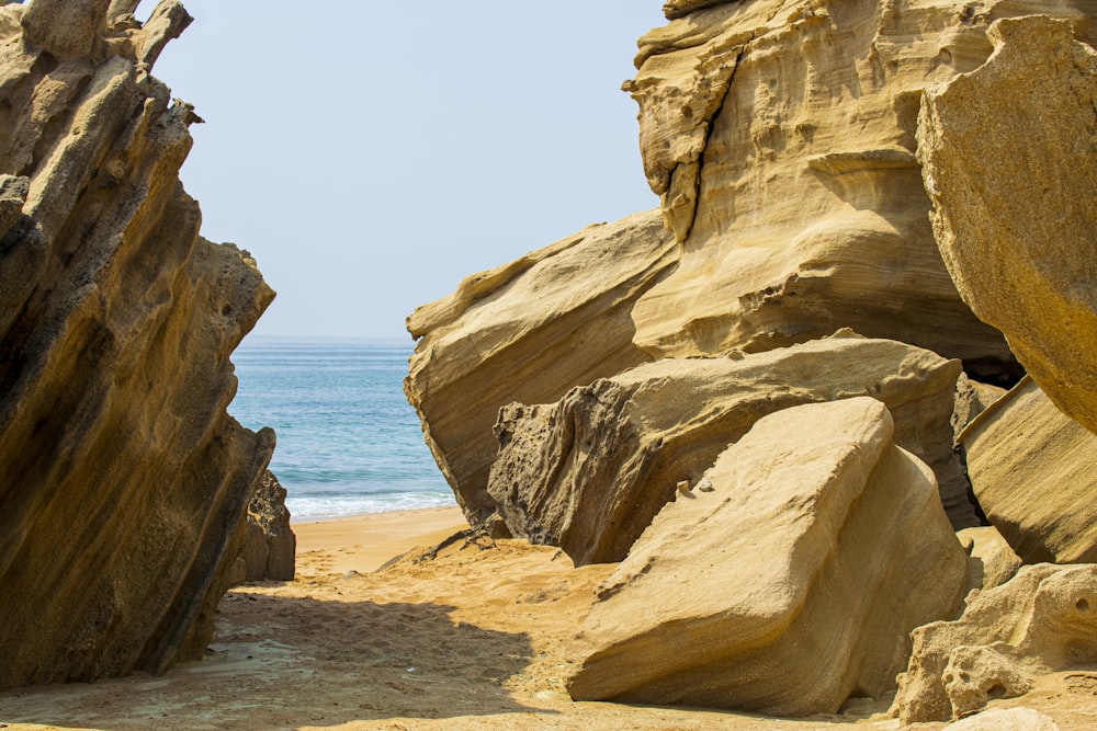 a large rock formation on a beach with the ocean in the background