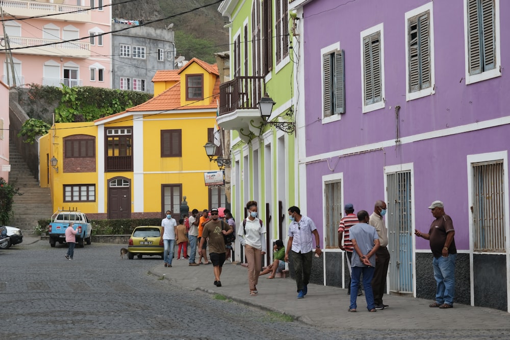 a group of people walking down a street next to colorful buildings