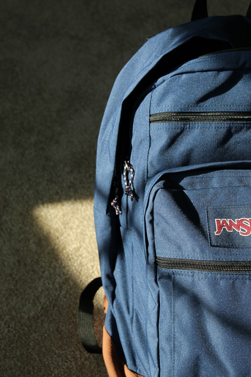 a blue jansport backpack sitting on the ground
