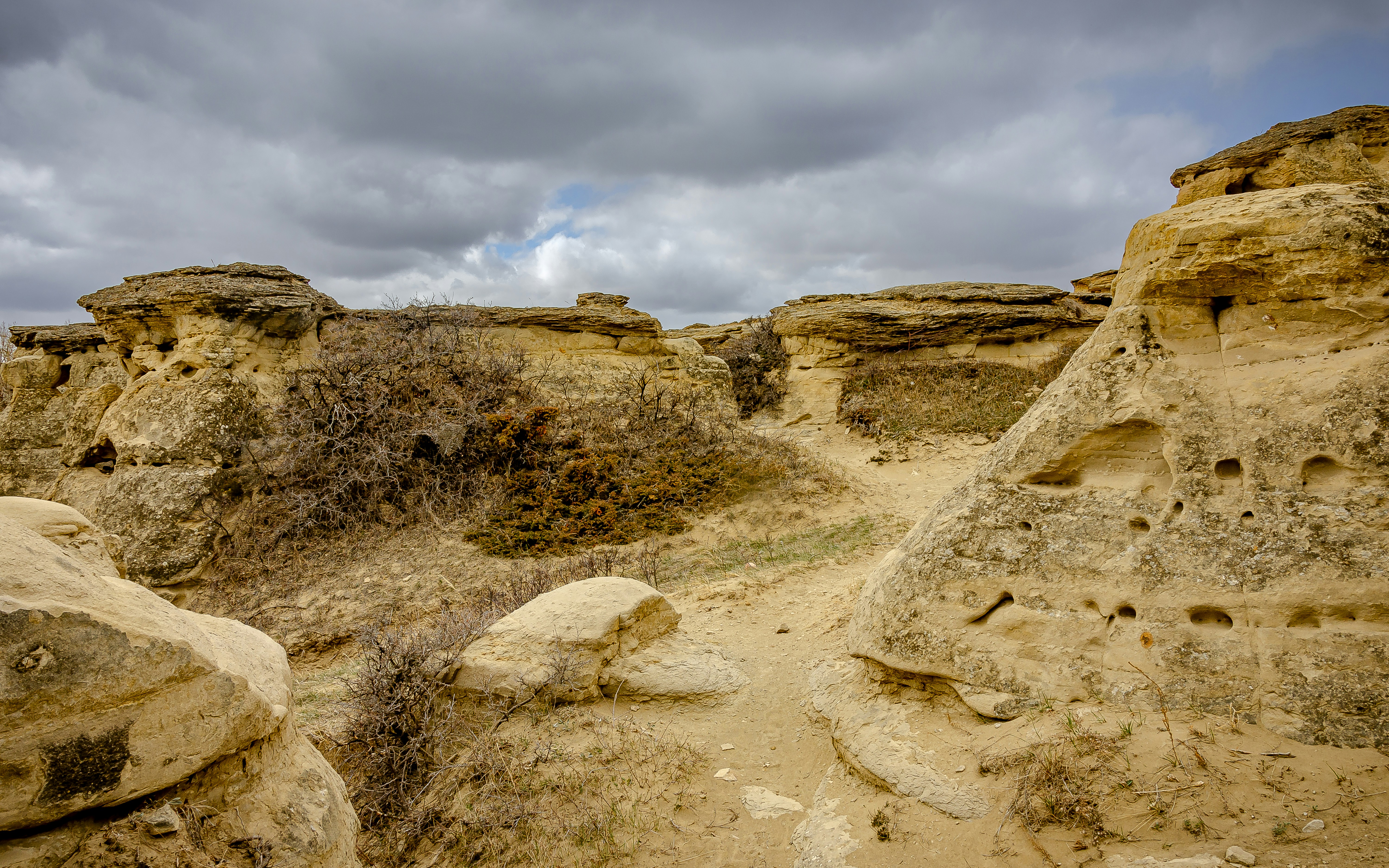 a group of rocks in the desert under a cloudy sky, 