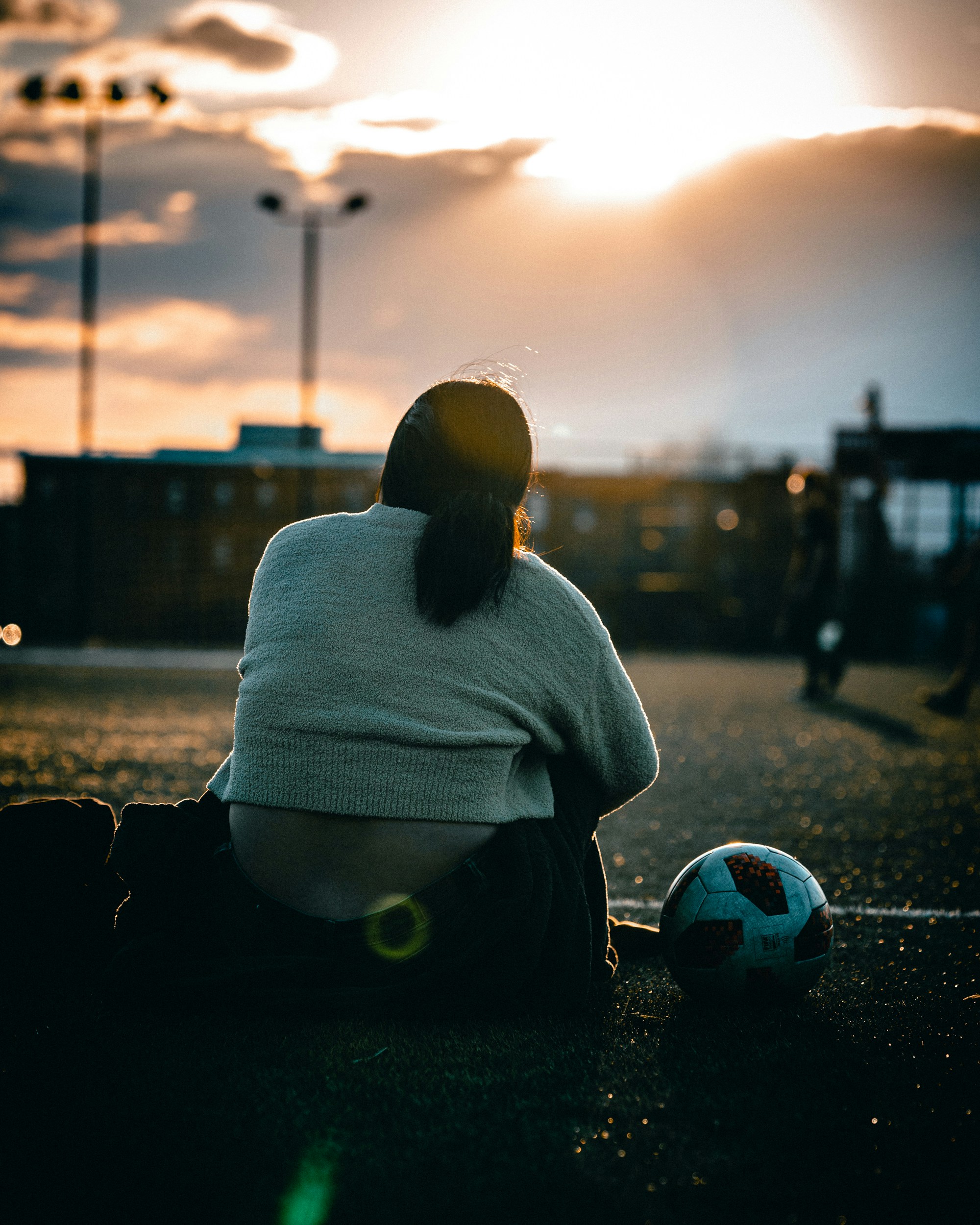 a woman sitting on the ground next to a soccer ball