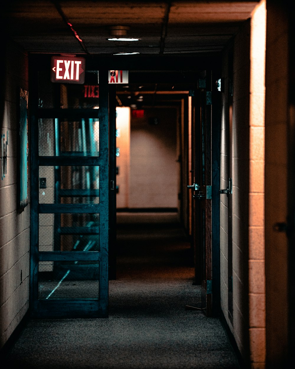 a hallway with a exit sign next to a book shelf