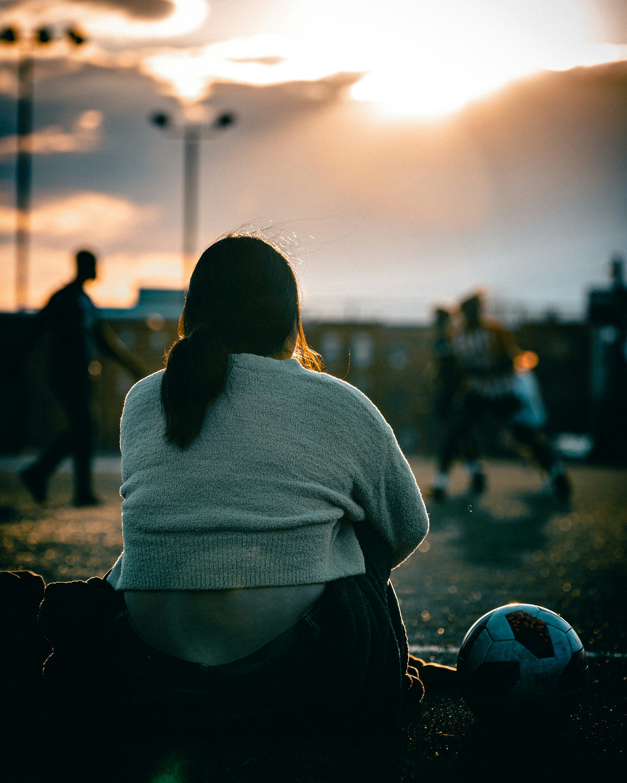 a woman sitting on the ground next to a soccer ball