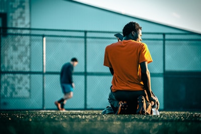 a man sitting on a bench in front of a fence