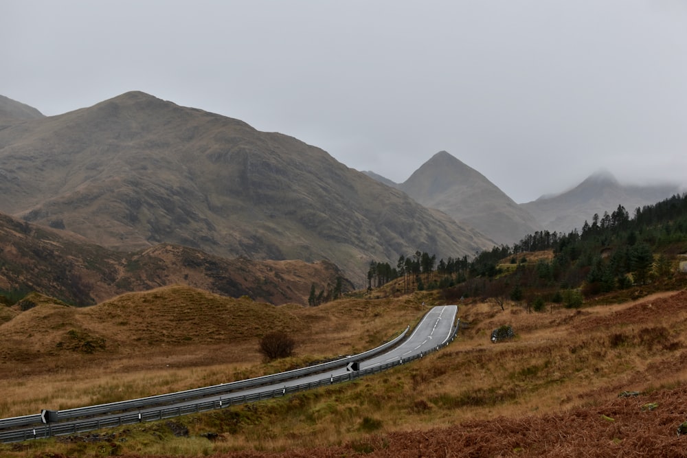 a long road going through a valley with mountains in the background