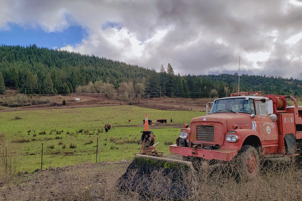 a red truck parked on top of a lush green field