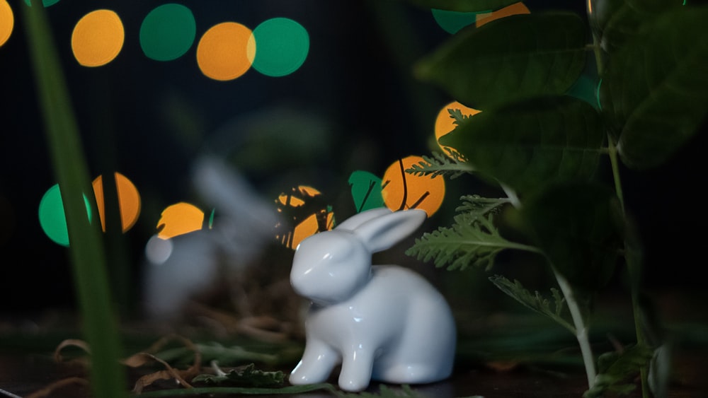 a small white rabbit figurine sitting in the grass