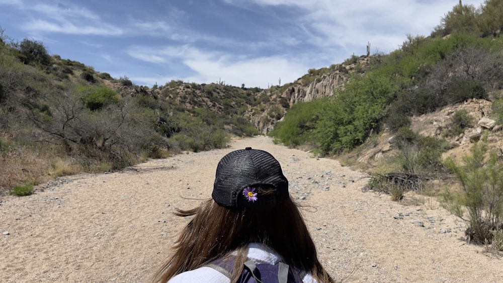 a person with a hat and backpack on a dirt road
