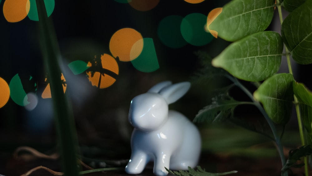 a small white rabbit figurine sitting in the grass