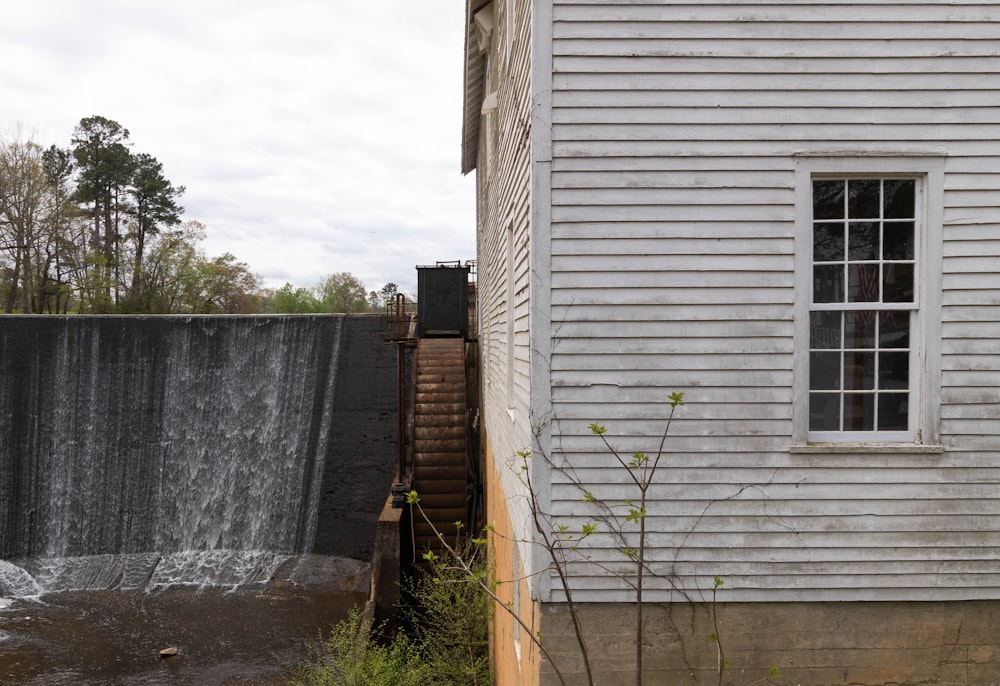 a white house next to a large waterfall