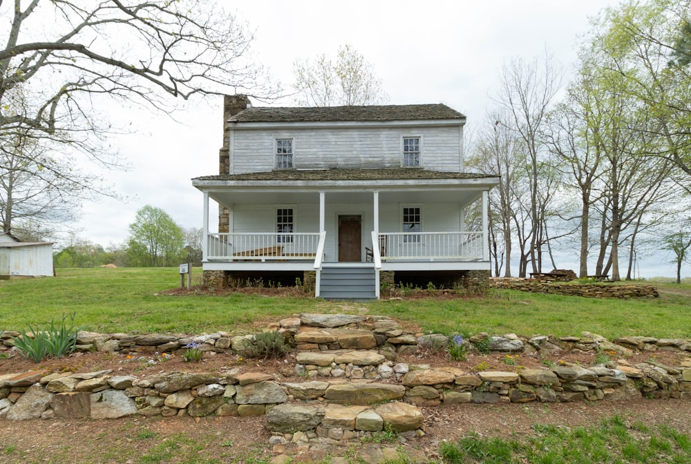 a white house with a porch and a stone wall