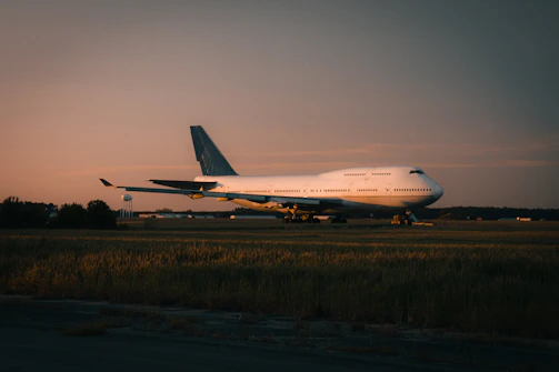 A light aircraft resting on a calm airstrip at dusk with gentle yellow light.