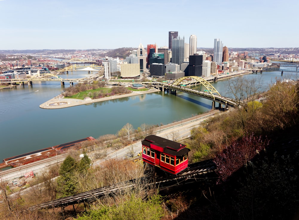 a red trolley car traveling down tracks next to a river