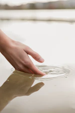 Close-up of hands gently touching water surface, creating calming waves.