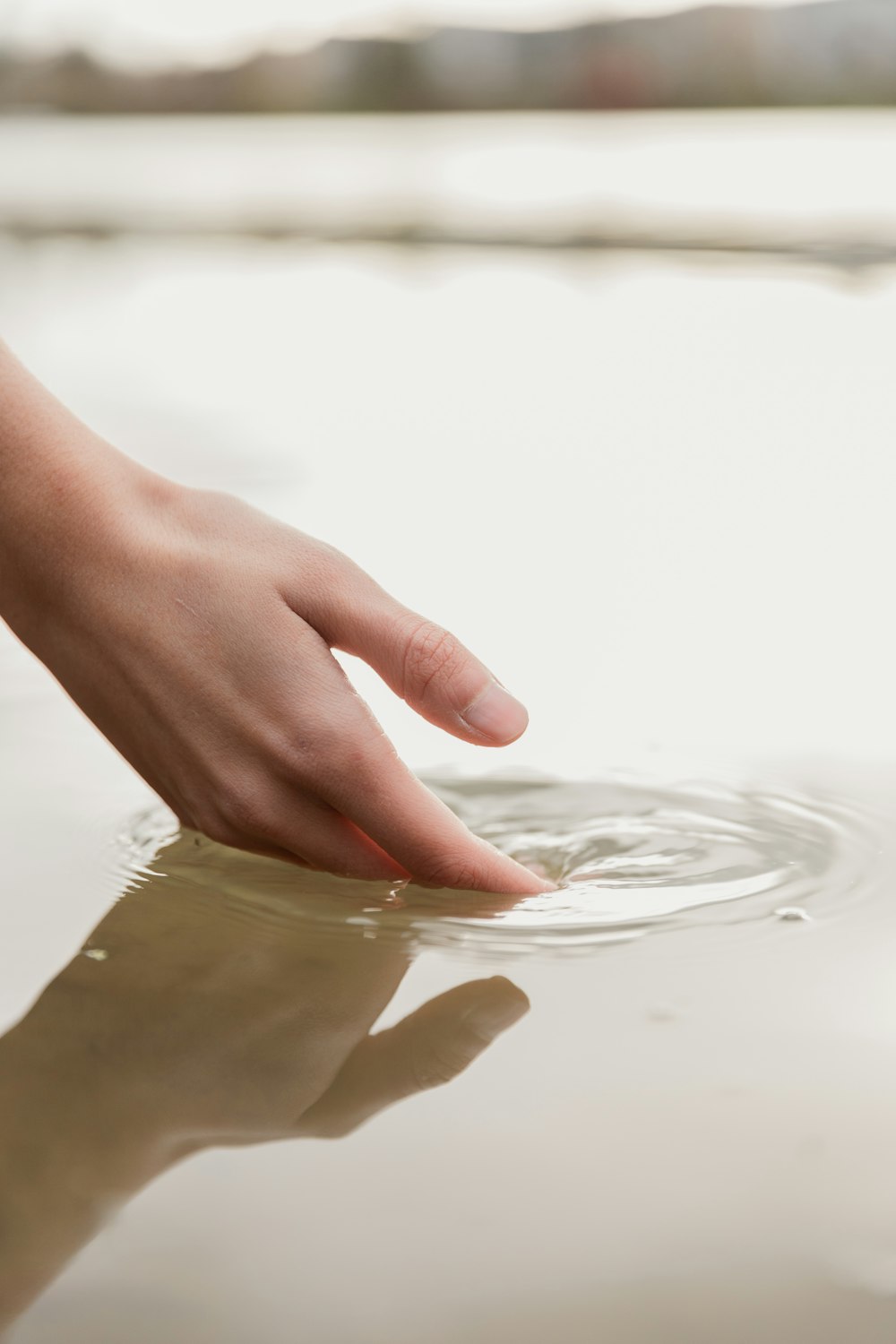 a person's hand reaching for a frisbee in the water