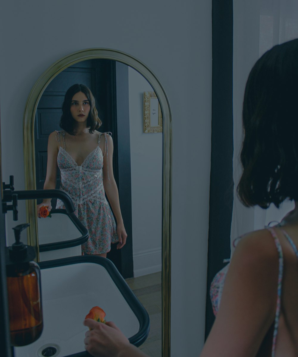 a woman standing in front of a mirror