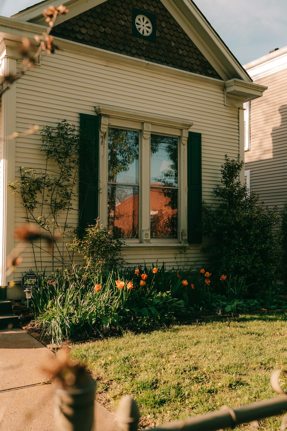 a white house with green shutters and a flower bed in front of it