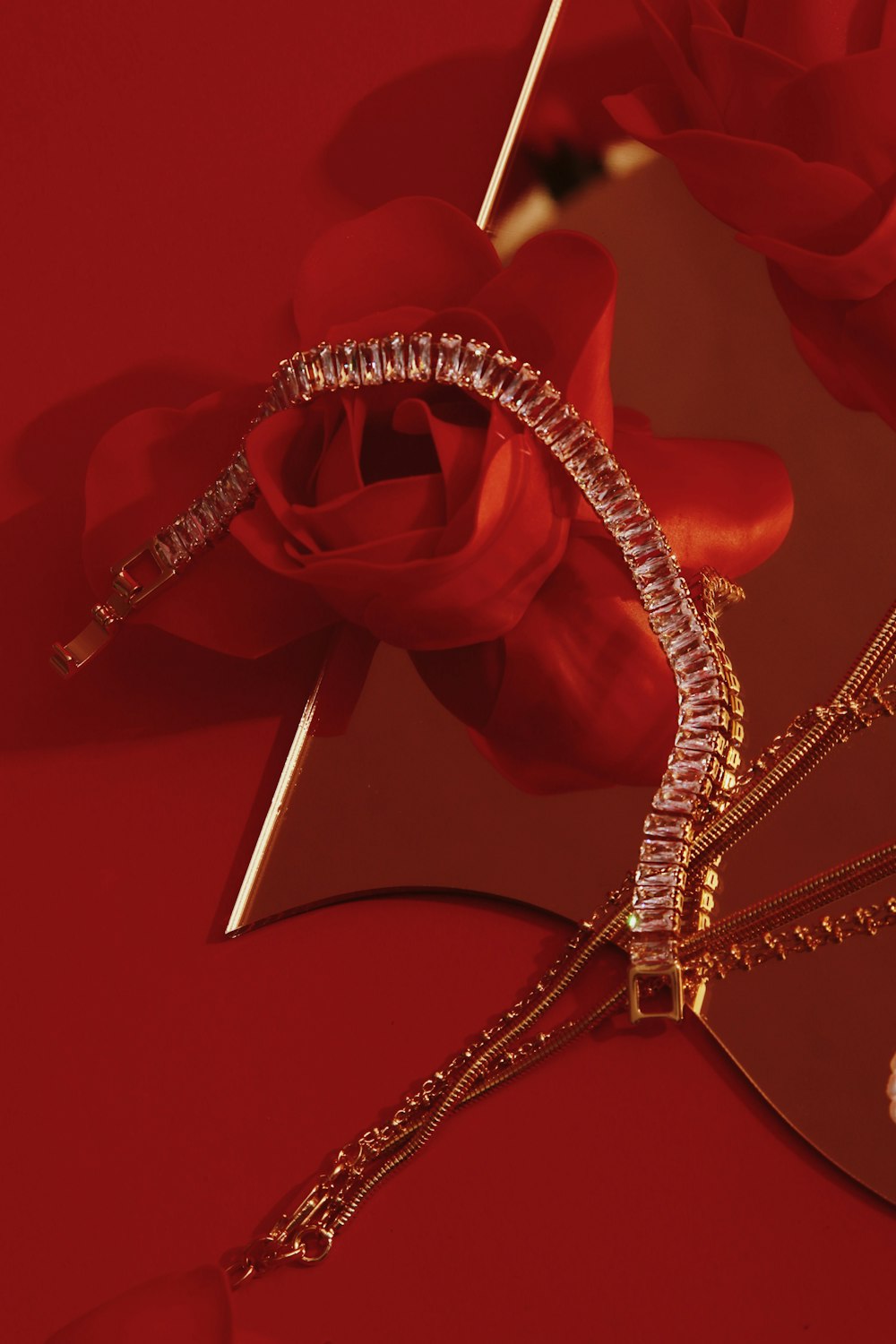 a close up of a red rose with a diamond necklace