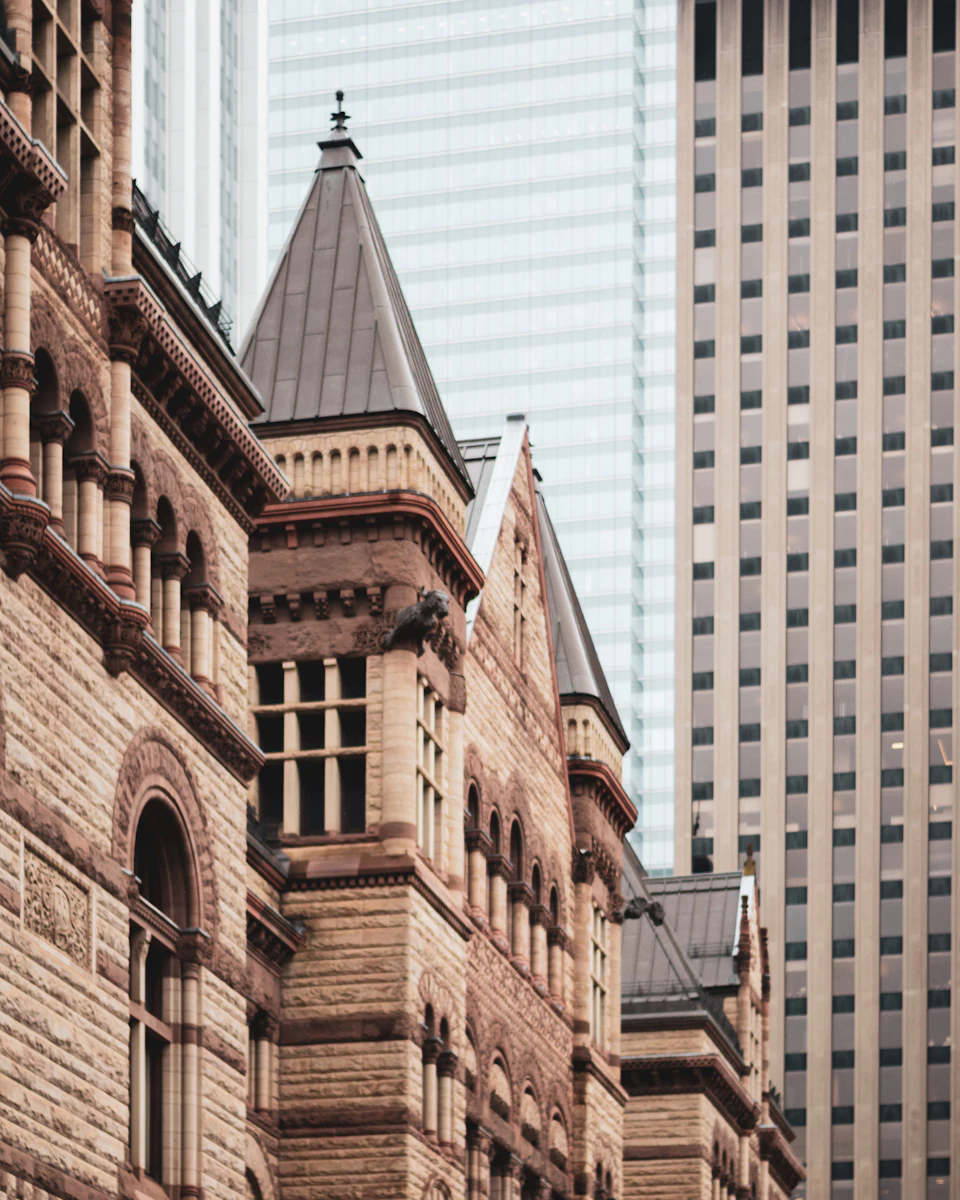Two contrasting city buildings stand side by side, one in brick with ornate details